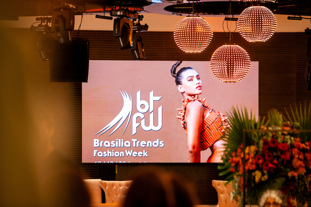 A imagem mostra o telão do Brasília Trends Fashion Week com uma modelo na foto de divulgação reproduzida na tela