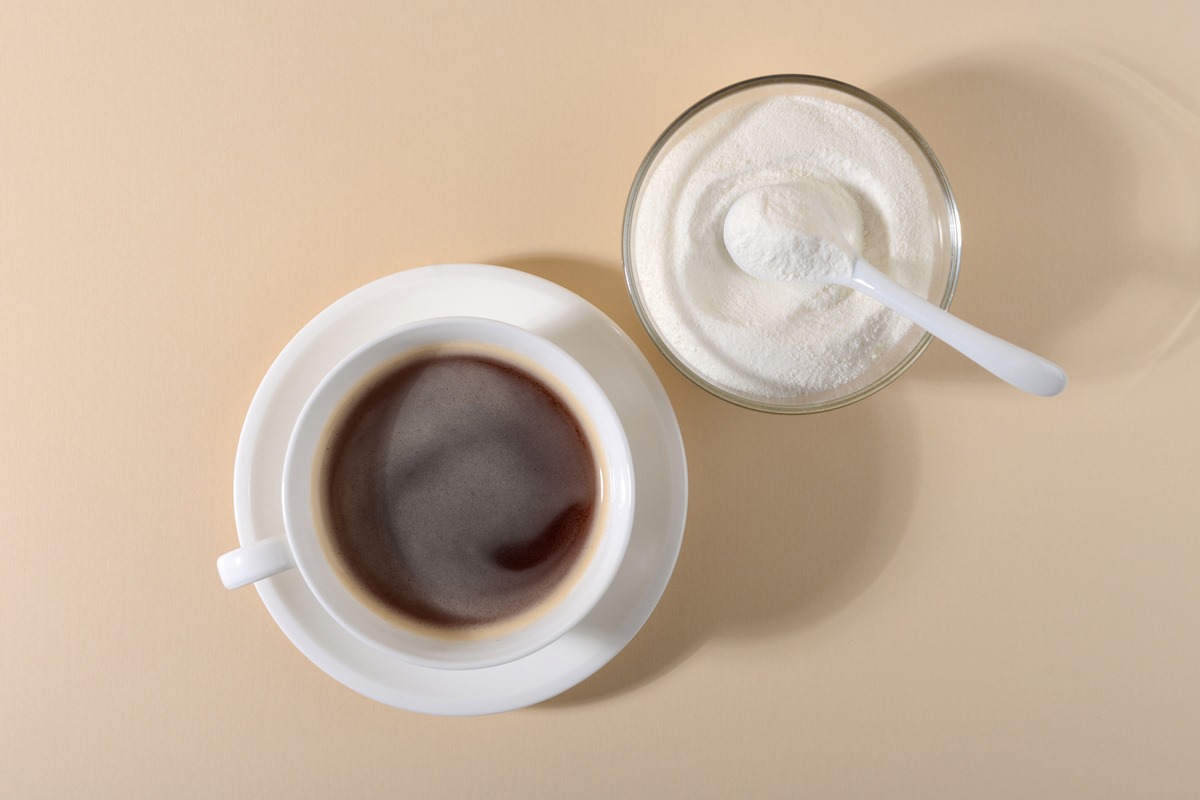 Foto colorida de xícara branca com café dentro e, ao lado, pote com pó branco - Metrópoles