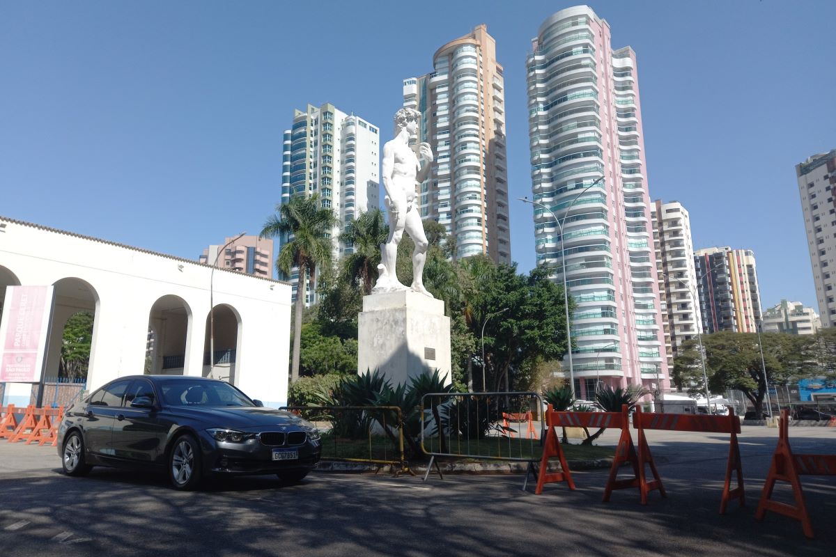 Imagem mostra carro, estátua e prédios ao fundo - Metrópoles