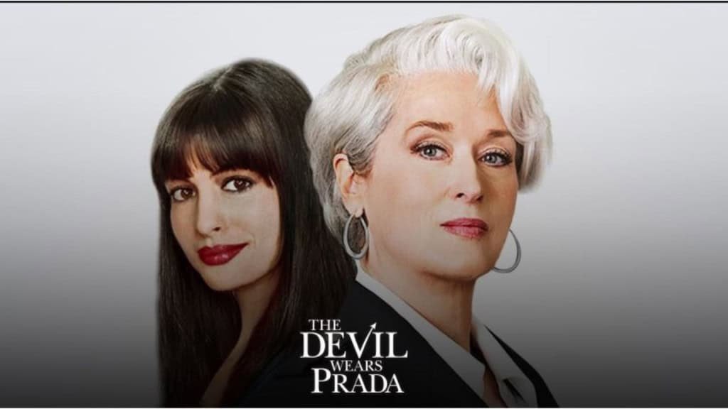 Na parte inferior da imagem, aparece o título em letras grandes: "THE DEVIL WEARS PRADA" — que traduzido para o português é "O Diabo Veste Prada".

🎬 Essa é a capa do famoso filme que retrata o mundo da moda, focando na relação entre uma jovem assistente e sua chefe poderosa e exigente. A imagem simboliza o contraste entre os dois personagens principais: juventude versus autoridade, ingenuidade versus experiência.