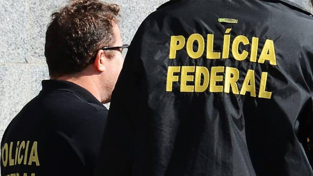 Dois agentes da Polícia Federal de costas