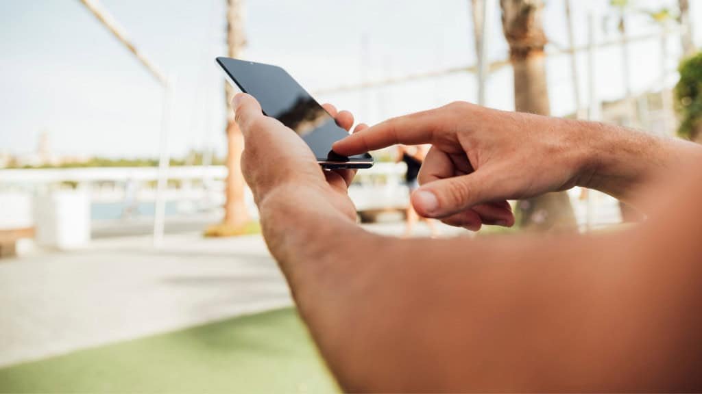 Imagem de das mãos de alguém que segura e mexe na tela do celular