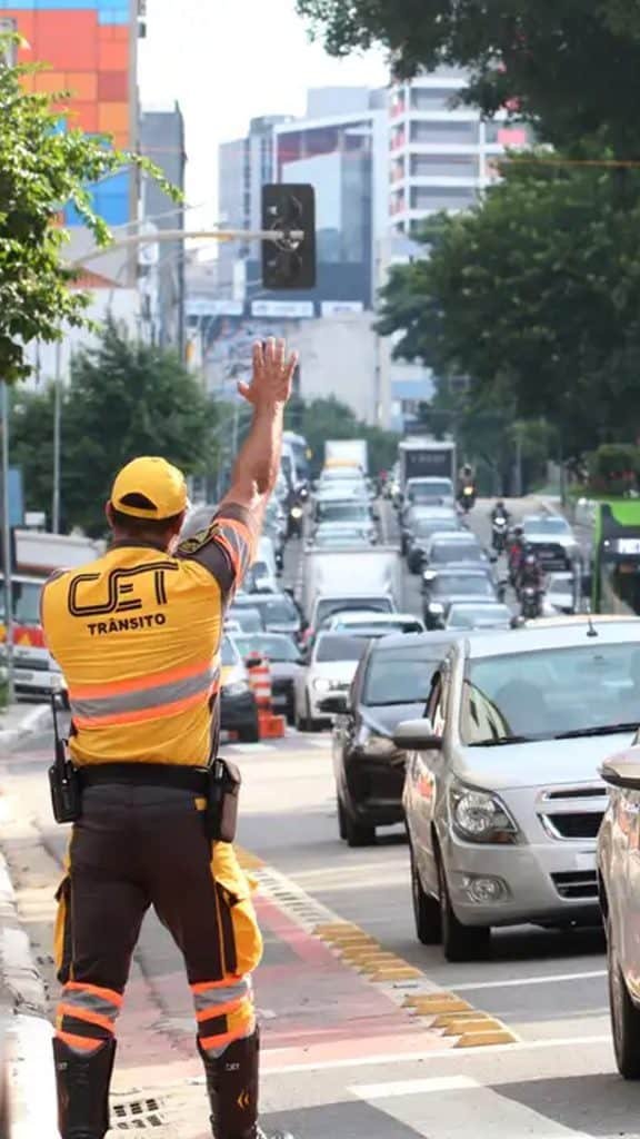 Guarda de trânsito com braço levantado em avenida em São Paulo