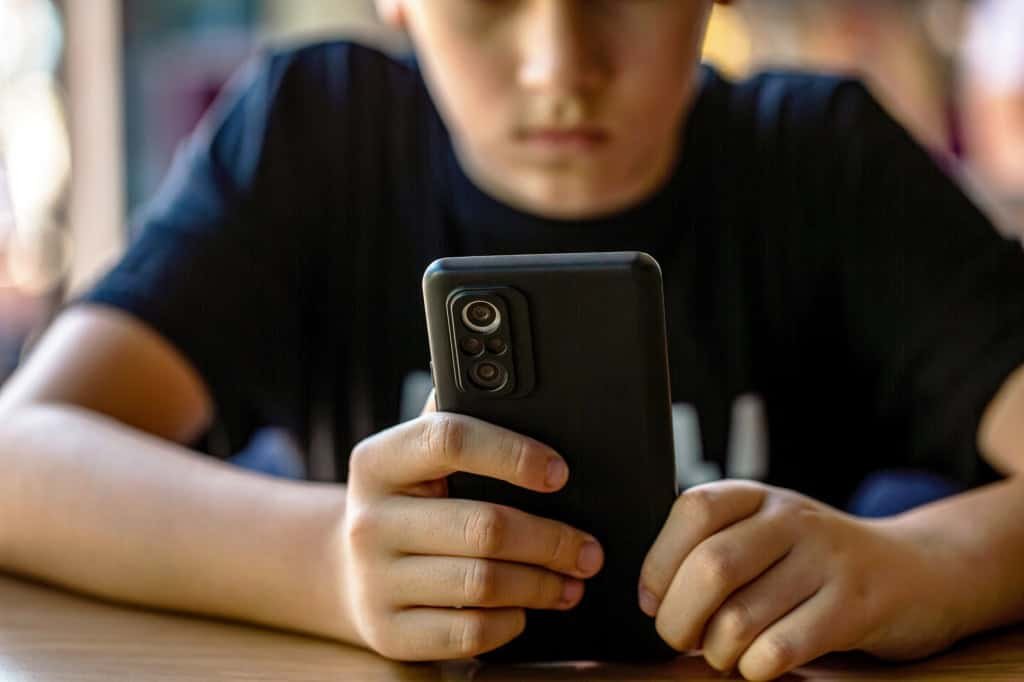 jovem no celular com o rosto desfocado