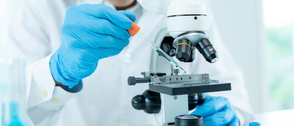 Pesquisador olhando substância no microscópio