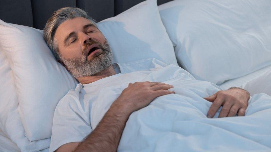 Homem roncando enquanto dorme na cama em casa