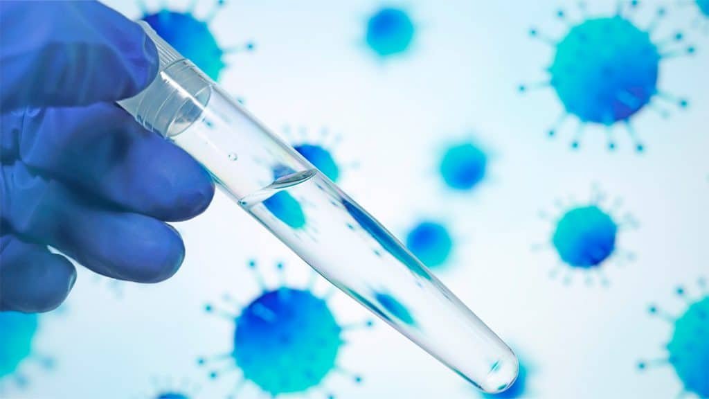 Cientista segurando frasco de laboratório e, ao fundo, desenhos de moléculas de vírus
