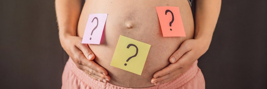 Barriga de grávida com post-its de ponto de interrogação colados