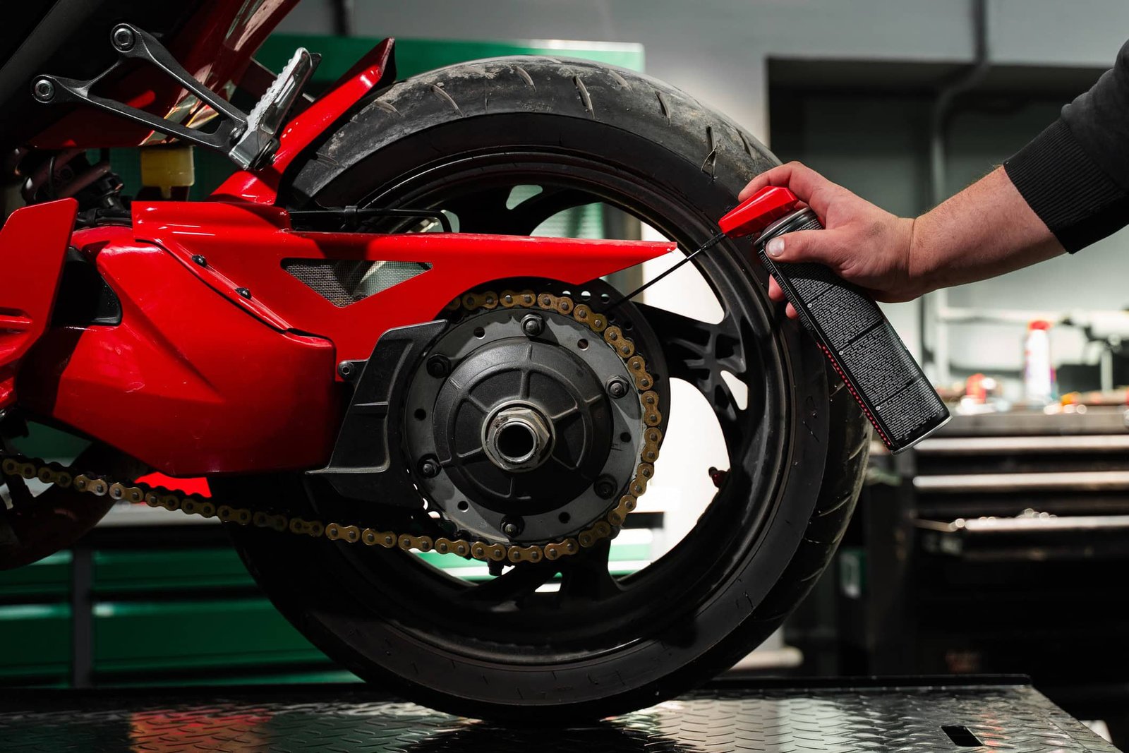 Pessoa faz lubrificação da corrente da moto